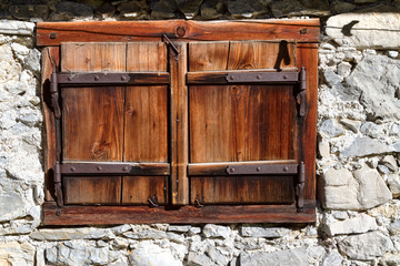 Closed vintage window on stone wall a house. Outdoors alpine scene, Austria, Tyrol.