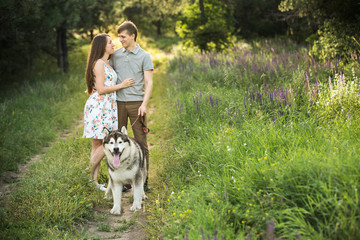 Naklejka na ściany i meble couple in love with a dog, Husky Malamute, sunset forest