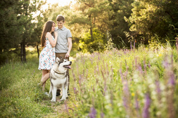 Naklejka na ściany i meble couple in love with a dog, Husky Malamute, sunset forest