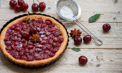 Summer dessert. Homemade cherry pie,  tart   with powdered sugar and star anise. Rustic style

