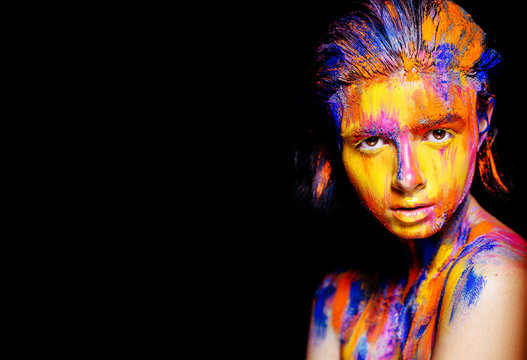 Art makeup. Face, neck and hair girls smeared with bright colors of yellow, blue and pink colors. Holi Festival