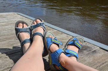 Füße in Sandalen - Verweilen am Wasser auf Bootssteg