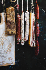 Charcuterie products hanging from dark country fall.