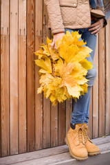 Closeup of beautiful yellow maple wreath in woman's hands. Girl holding  autumn leaves. Fall and lifestyle concept