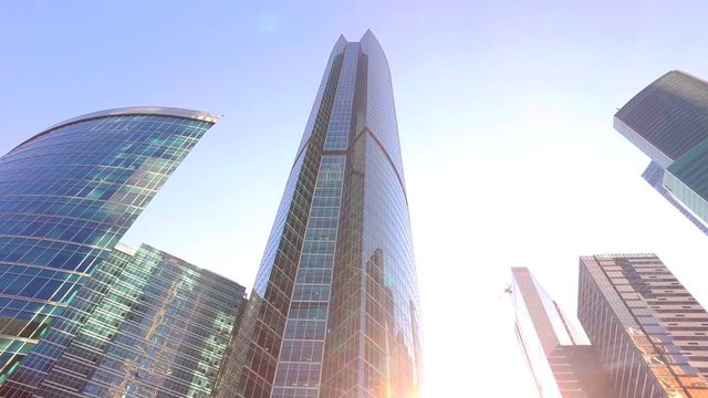 Moving among the skyscrapers and luxury offices with sun rays (low angle dolly shot, slow motion)