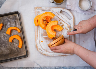 Female hand cut pumpkin on a cutting board, ready to baked.