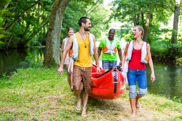 Freunde tragen zusammen Kajak zum Wald Fluss