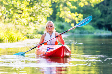 Woman driving with kayak on forest river - obrazy, fototapety, plakaty