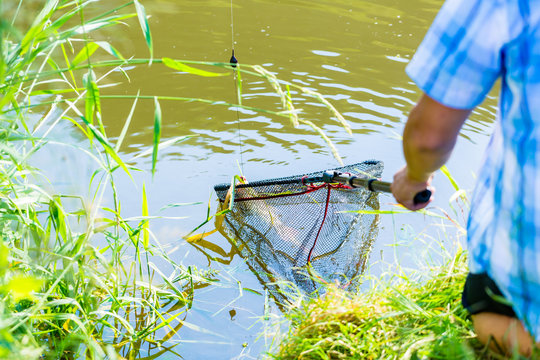 Sport fisherman getting his catch out of the water with dip