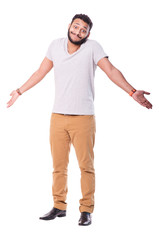 Uncertain latino man with beard. Wears beige pants and grey t-shirt. Full length portrait. Isolated on white background.