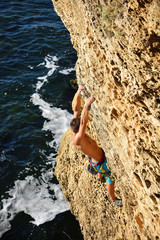 athletic man climbing on a rock