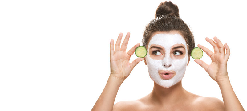 Woman with facial mask and cucumber slices in her hands