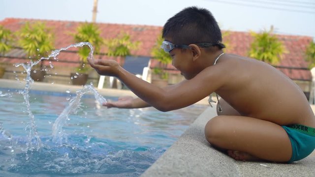 Little boy sits near swimming pool and plays with water 4k UHD (3840x2160) 
