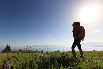 Fototapeta premium successful woman backpacker hiking on mountain peak