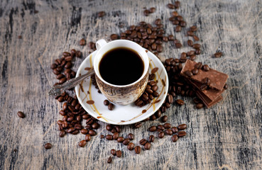 Чашка кофе и шоколад на фоне зернового кофе