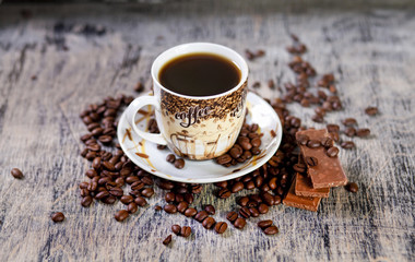 Чашка кофе и шоколад на фоне зернового кофе