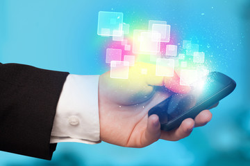 Hand holding smart phone with abstract glowing squares