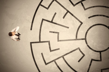 Lost business man looking for a way in circular labyrinth