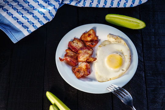 Fried egg with bacon, sliced cucumber and towel