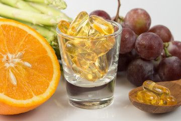 Vitamin Capsules with fruit on white
