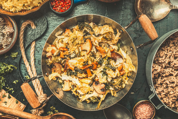 Cooking preparation of Casserole with stewed cabbage ,mushrooms and pot with minced meat  on dark rustic background, top view