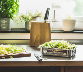 Chopped Savoy cabbage cooking preparation on kitchen table at window.