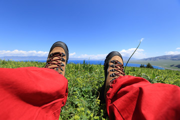 hiker sitting on a grass mountain top with first person perspective view
