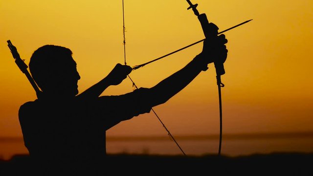 Archery silhouette, sun sets behind the archer. Young hunter./ Archery silhouette, sun sets behind the archer. Young hunter shoots a bow at sunset.