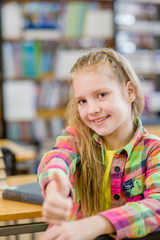 teen girl in library showing thumbs up