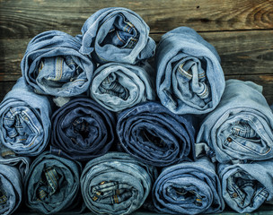 bunch of jeans twisted on a wooden background, fashionable clothes