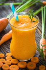 Homemade carrot juice with fresh carrots on wooden background