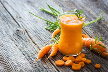 Homemade carrot juice with fresh carrots on wooden background
