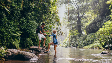 Man helping woman crossing stream