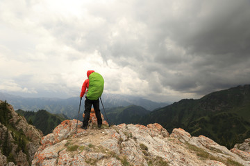 Obraz premium successful woman backpacker hiking on mountain peak cliff