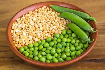 Yellow and green peas in a bowl on a wooden table