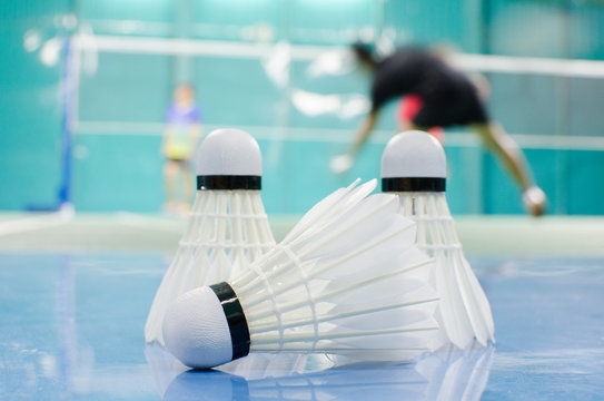shuttlecock on the floor with badminton player in court