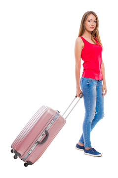 Young attractive woman in blue jeans with a suitcase isolated on white background.