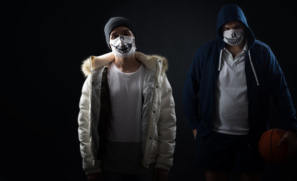 studio on a black background portrait of two men in masks with basketball