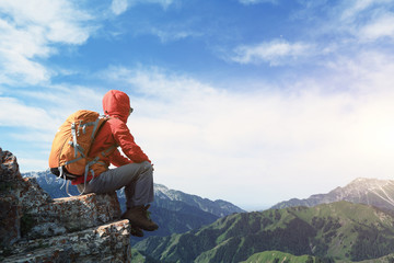 successful woman backpacker enjoy the view on mountain peak cliff