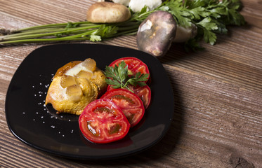Fried mushrooms with tomatoes on black plate