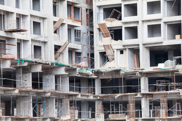 The technology or art of high rise apartment construction using crane, lift, metal beam, brick, metal ladder and concrete in construction site.