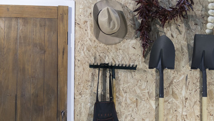 hoe, shovel, harrow and hat beside wooden door