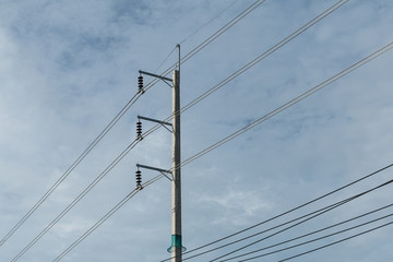 Electric pole and electricity line with against blue cloudy sky,