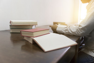 man reading book with textbook stack on wooden desk
