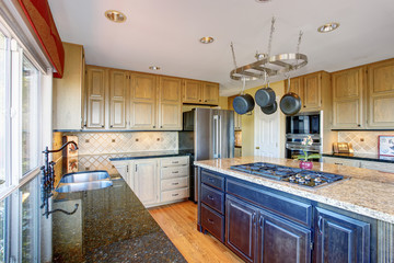 View of modern kitchen room interior with kitchen island and honey color cabinets.