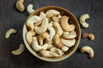 Bowl of cashew nuts from above. On wood background.