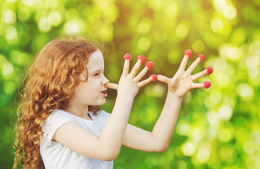 Little girl teasing is putting fingers to nose with raspberry.