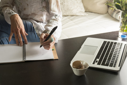 Woman hands writes a pen in a notebook, computer keyboard