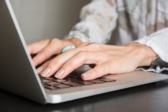 Woman hands writes a pen in a notebook, computer keyboard