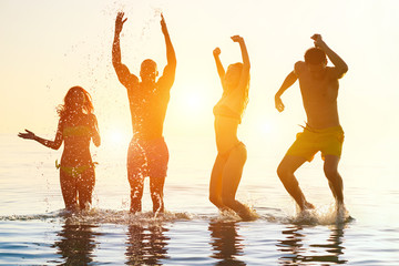 Young people swimming at sunrise party on the beach 
